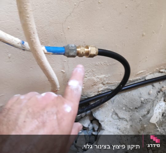 יד מצביעה על חיבור צינור מים עם מחבר מתכת